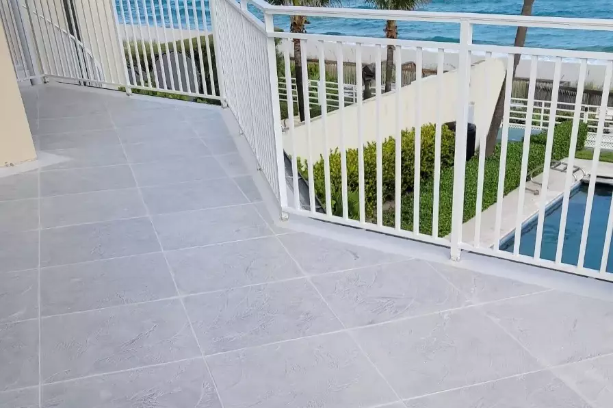 Oceanfront deck resurfaced with a light gray tile-pattern finish, pool below